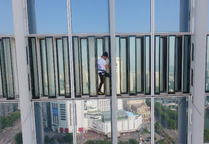알랭 로베르가 123층짜리 롯데월드타워를 무단으로 오르고 있다. 서울 송파경찰서는 6일 롯데 측과 협의없이 555m에 달하는 롯데월드타워 외벽을 75층까지 등반한 로베르를 업무방해 혐의로 입건했다. 사진: 서울소방재난본부/뉴시스