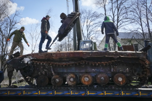 11일(현지시간) 우크라이나 키이우 인근 안드리우카에서 도로 작업자들이 파괴된 러시아군 전차를 대형 트럭에 실어 치우고 있다. 우크라이나군은 전쟁 초 러시아군이 점령했던 안드리우카를 최근 탈환했다. AP