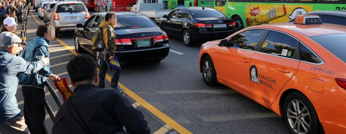 카카오 카풀 서비스에 반발하는 전국 택시업계가 파업에 돌입한 지난 18일 오후 청와대로 행진하던 참가자가 운행중인 택시에 다가가 항의하고 있다. 뉴시스