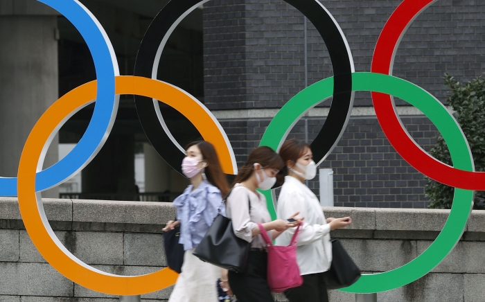 23일 개막하는 2020 도쿄올림픽은 코로나19 긴급 사태 발령 속에서 무관중 경기가 예고돼 있다. 코로나19 확산 방지를 위해 마스크를 쓴 일본 시민들이 지난 8일 도쿄올림픽 오륜 조형물 앞을 지나가는 모습. AP/뉴시스